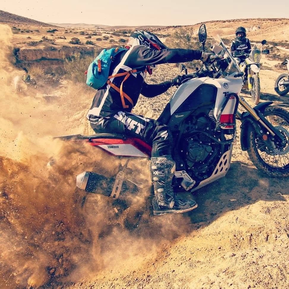 A wave of desert sand roosting off the rear wheel of a Tenere 700