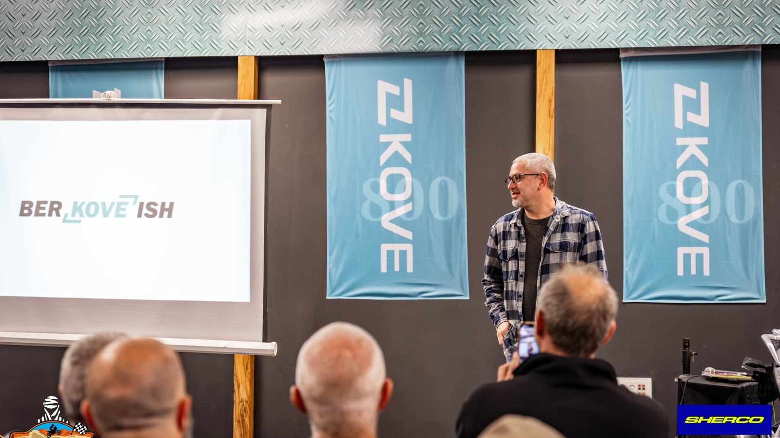 David presenting on stage at the KOVE importer event, a BER-KOVE-ISH slide behind him